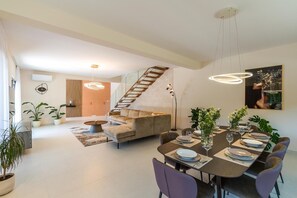 Un intérieur moderne comprenant un coin repas, un canapé, un escalier et des plantes en pot.