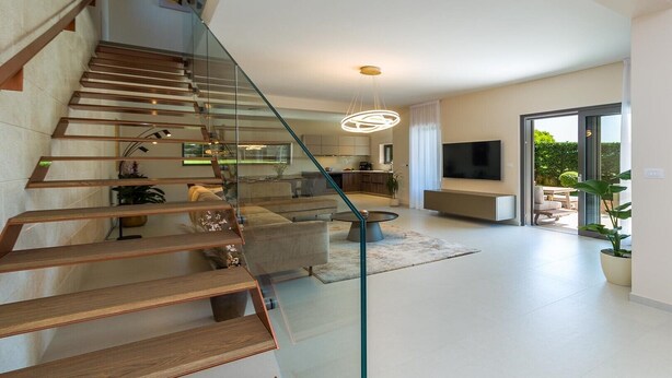A modern interior with a staircase, a living area, and a dining space.