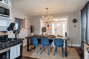 A modern kitchen with a black stove, blue chairs, a chandelier, and a dining table. - 21 - 2Bd Retreat Near KU Med 21 (Kansas City)