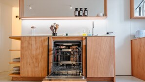 A modern kitchen with a built-in dishwasher, wooden cabinetry, and a countertop with kitchen utensils. - Babylon Montmartre (Paris)
