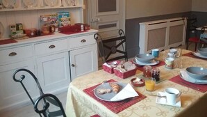 Un coin repas avec une table mise pour le petit-déjeuner, comprenant du pain, des croissants et du jus de fruits.