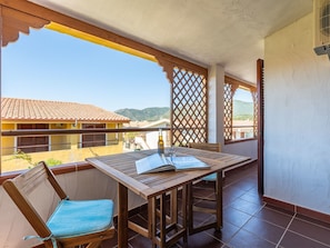 Ein Balkon mit Tisch, Stühlen und einer Bierflasche.