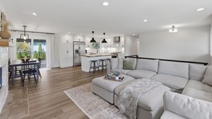 A modern living room with a sofa, dining table, and kitchen area. - Family Get Away Fireplace Near Columbia River 4 Bedroom Home (Vancouver)