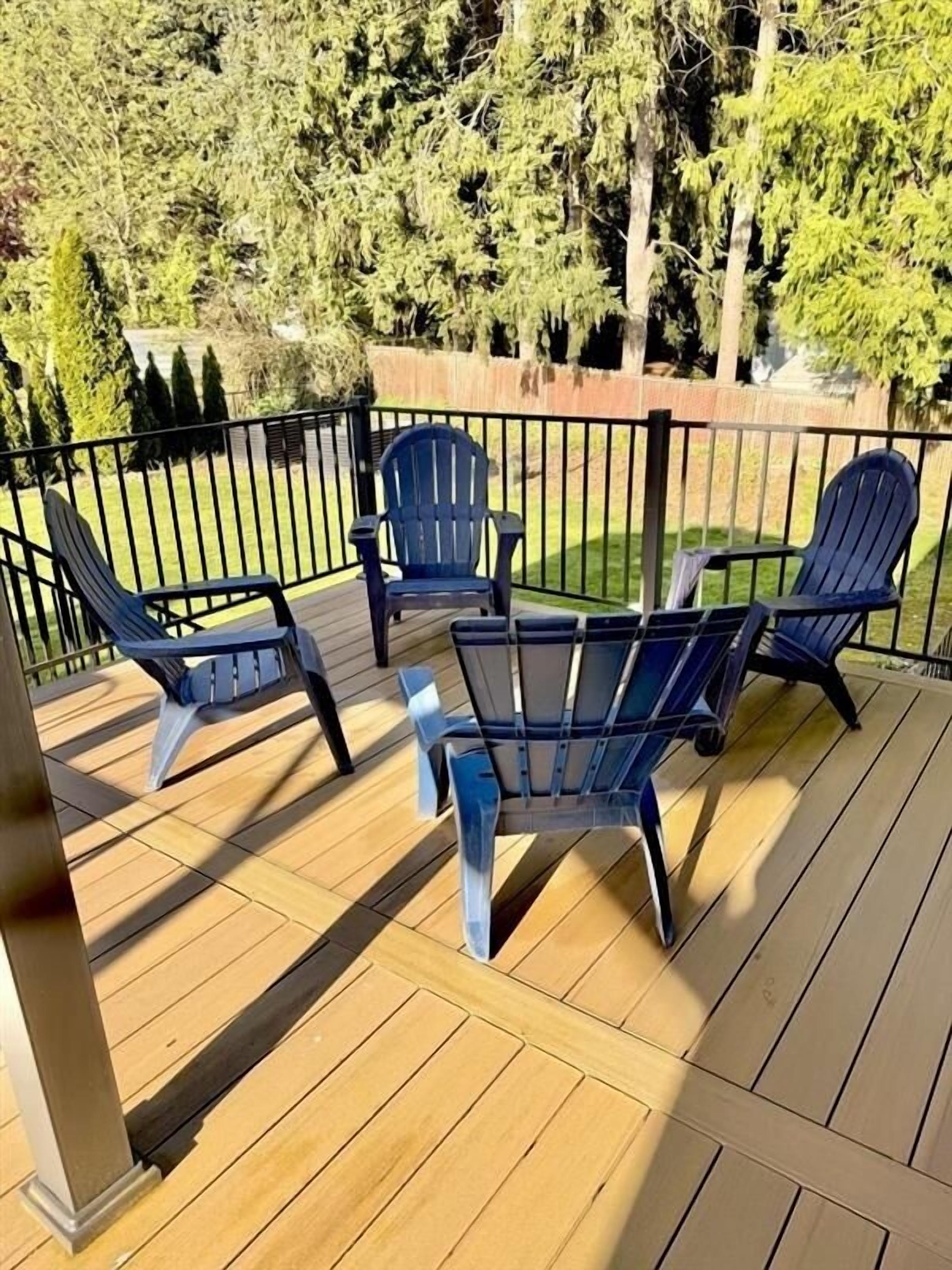 A wooden deck with four Adirondack chairs and a table.