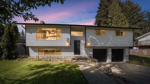 A modern two-story house with a garage, a well-maintained lawn, and a clear sky. - Family Get Away Fireplace Near Columbia River 4 Bedroom Home (Vancouver)