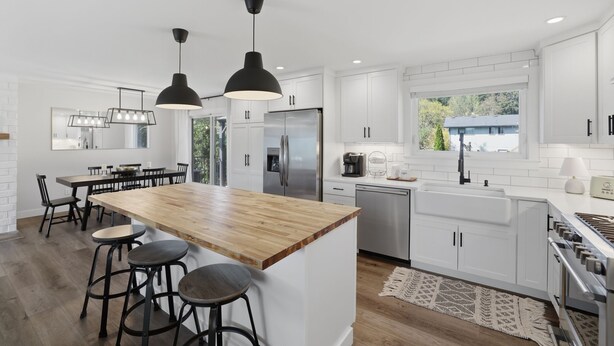 A modern kitchen with white cabinets, a wooden island, black pendant lights, and stainless steel appliances. - Family Get Away Fireplace Near Columbia River 4 Bedroom Home (Vancouver)