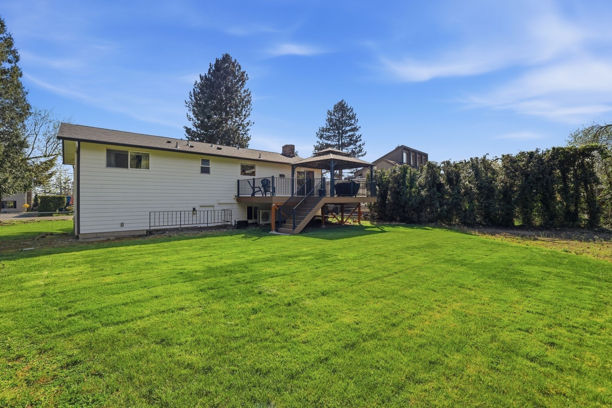 A single-story house with a covered porch, a fenced yard, and a well-maintained lawn.