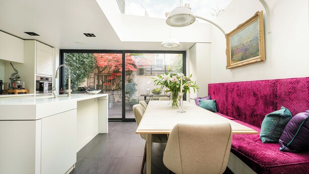Eine moderne Küche mit Essbereich, einem großen Fenster und einem roten Sofa.