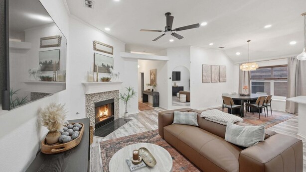 En moderne stue med pejs, sofa, sofabord og spiseplads med stole.