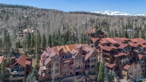 A mountainous lodge with multiple buildings, large windows, and a snowy mountain backdrop. - Slopeside Reserve 2 Bedroom Condo (Telluride)