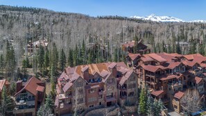 A mountainous lodge with multiple buildings, large windows, and a snowy mountain backdrop. - Trails Edge 8 2 Bedroom Condo (Telluride)