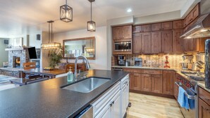 A modern kitchen with a large island, wooden cabinets, stainless steel appliances, and pendant lighting. - Slopeside Reserve 2 Bedroom Condo (Telluride)