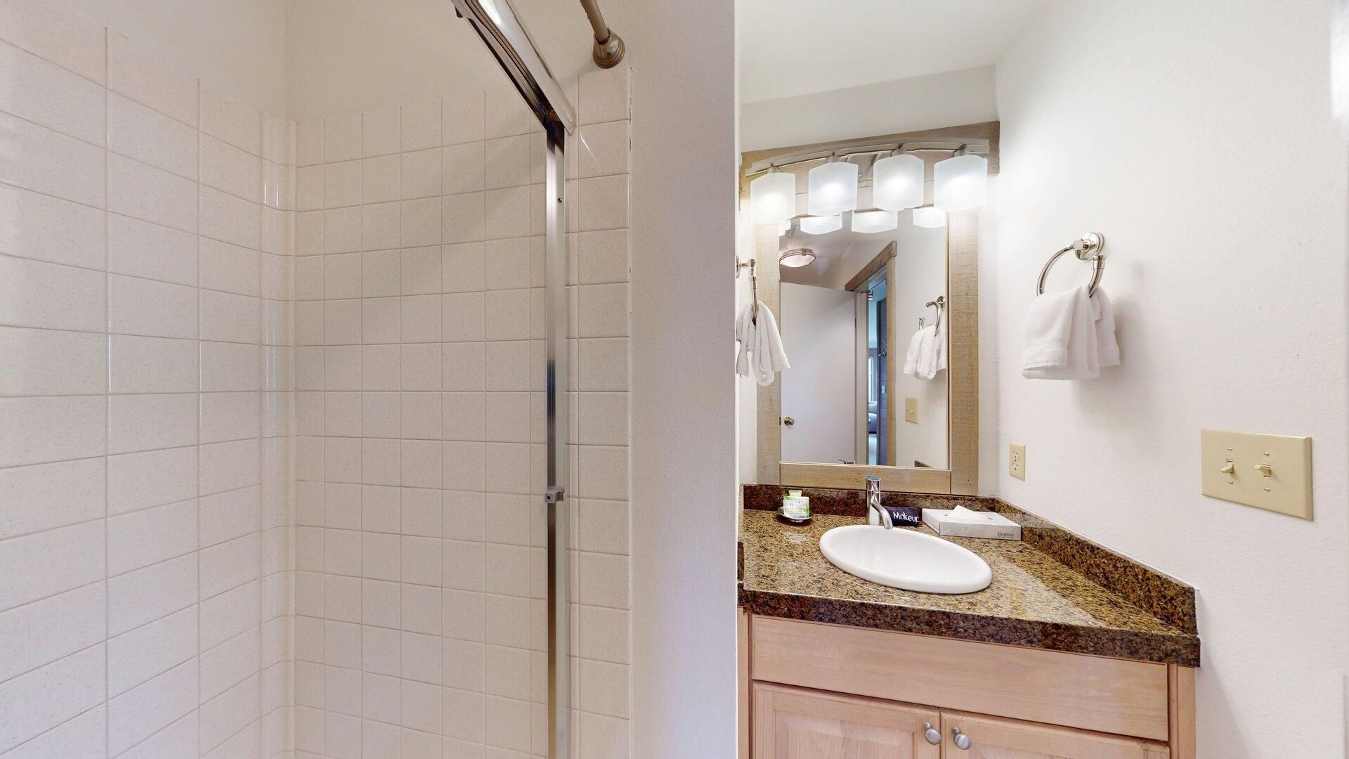 A bathroom with a shower, a sink with a mirror, and a towel rack.