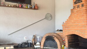 Un four en briques, une enseigne, un téléviseur et des étagères remplies de bouteilles et de boîtes de conserve.