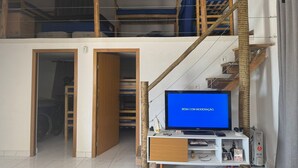Une chambre aménagée en mezzanine avec une télévision, un bureau et un escalier.