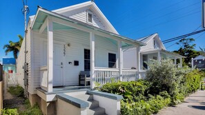 A white two-story house with a covered porch and a small front yard.