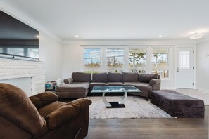 Ein modernes Wohnzimmer mit einer Eckcouch, einem Glastisch und einem Kamin.
