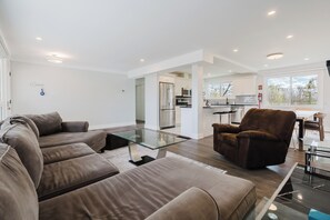 A modern living room with a sectional sofa, a glass coffee table, and a brown armchair.