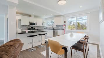 Una cocina moderna con armarios blancos, electrodomésticos de acero inoxidable y un amplio ventanal.