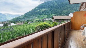 Un balcon offrant une vue sur un paysage montagneux, avec une balustrade en bois et un sol carrelé.