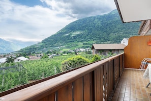 Ein Balkon mit Blick auf eine gebirgige Landschaft, einem Holzgeländer und einem gefliesten Boden.