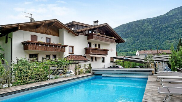 Un hôtel doté d’une piscine, d’une terrasse en bois et offrant une vue sur les montagnes.
