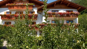 Un immeuble à plusieurs étages, doté de balcons ornés de fleurs et entouré de verdure.