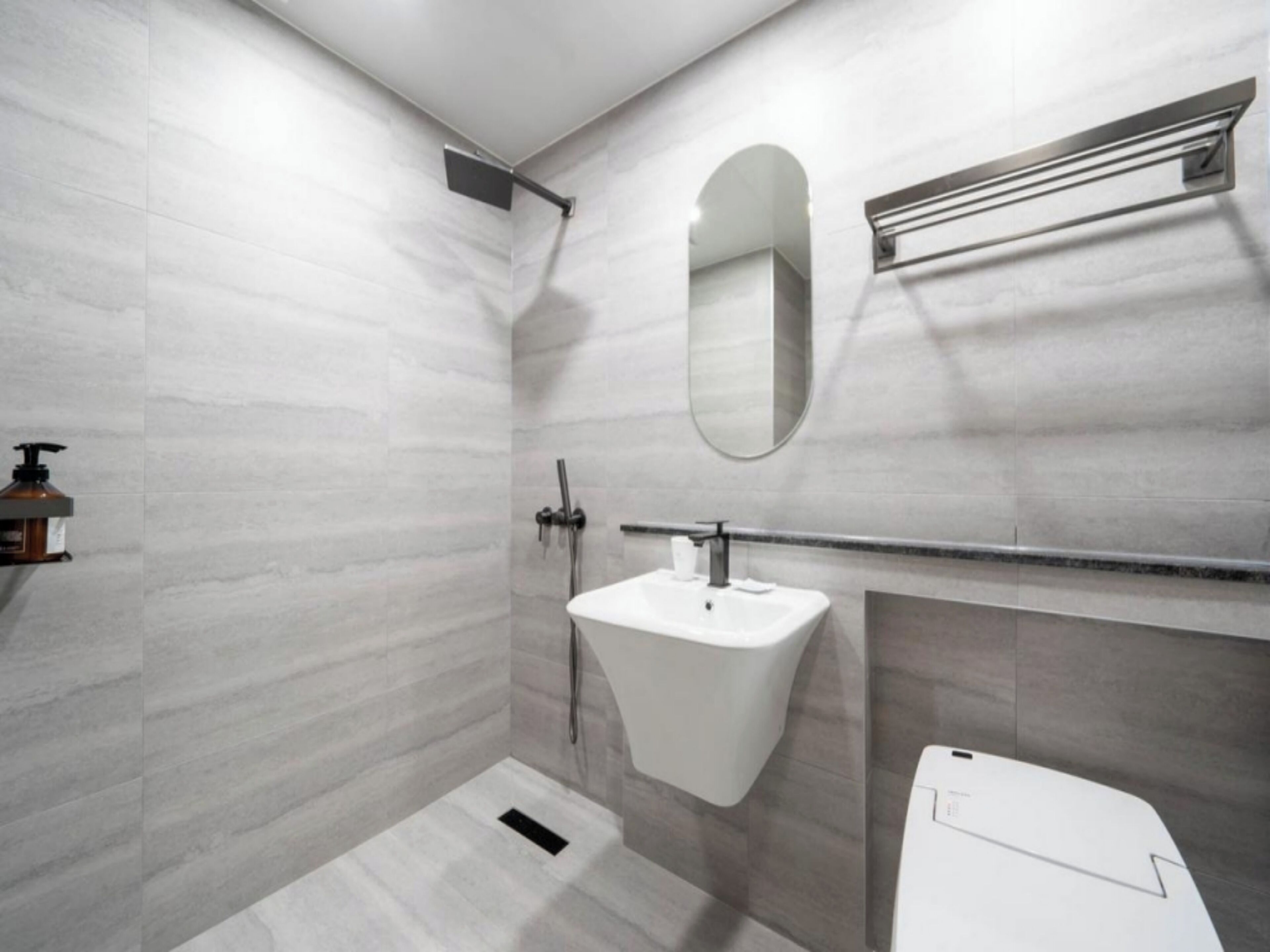 Une salle de bain moderne avec un lavabo blanc, un miroir et un espace douche.