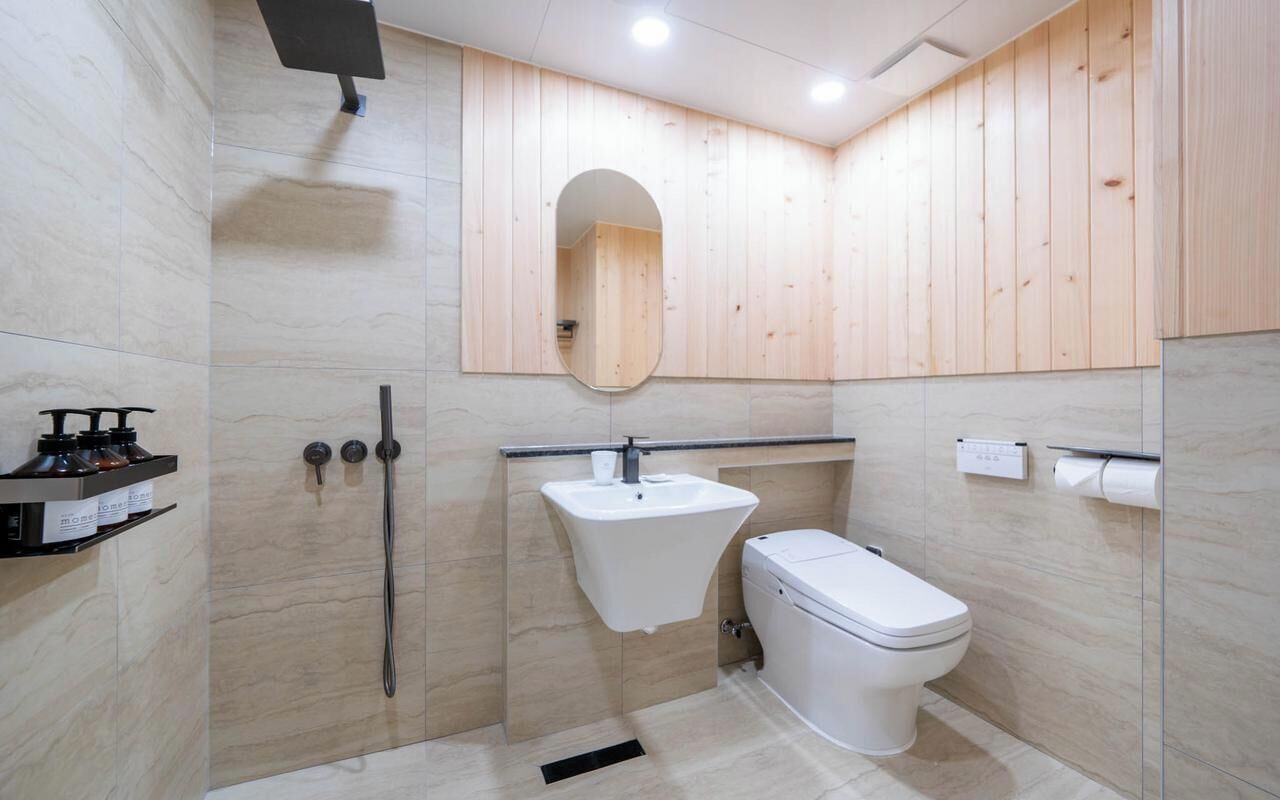 Een moderne badkamer met douche, wastafel, toilet en houten lambrisering.