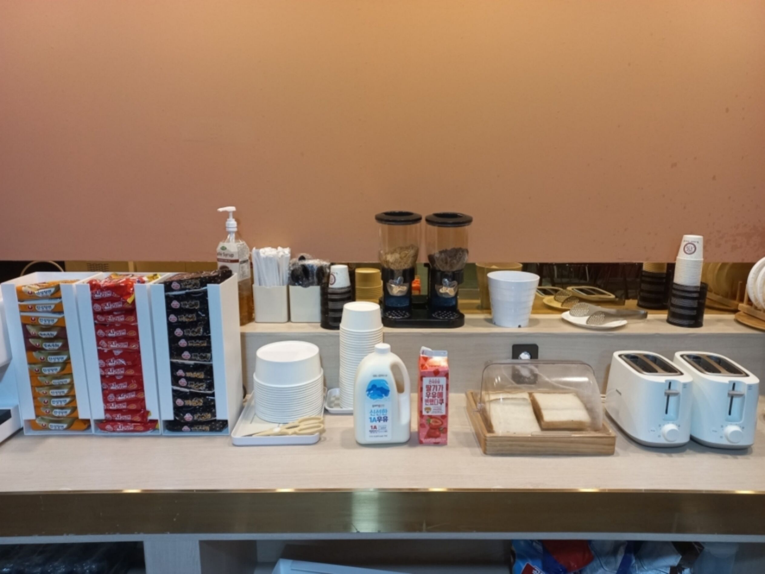 Een ontbijtbalk met koffiezetapparaten, broodroosters en toevoegingen.