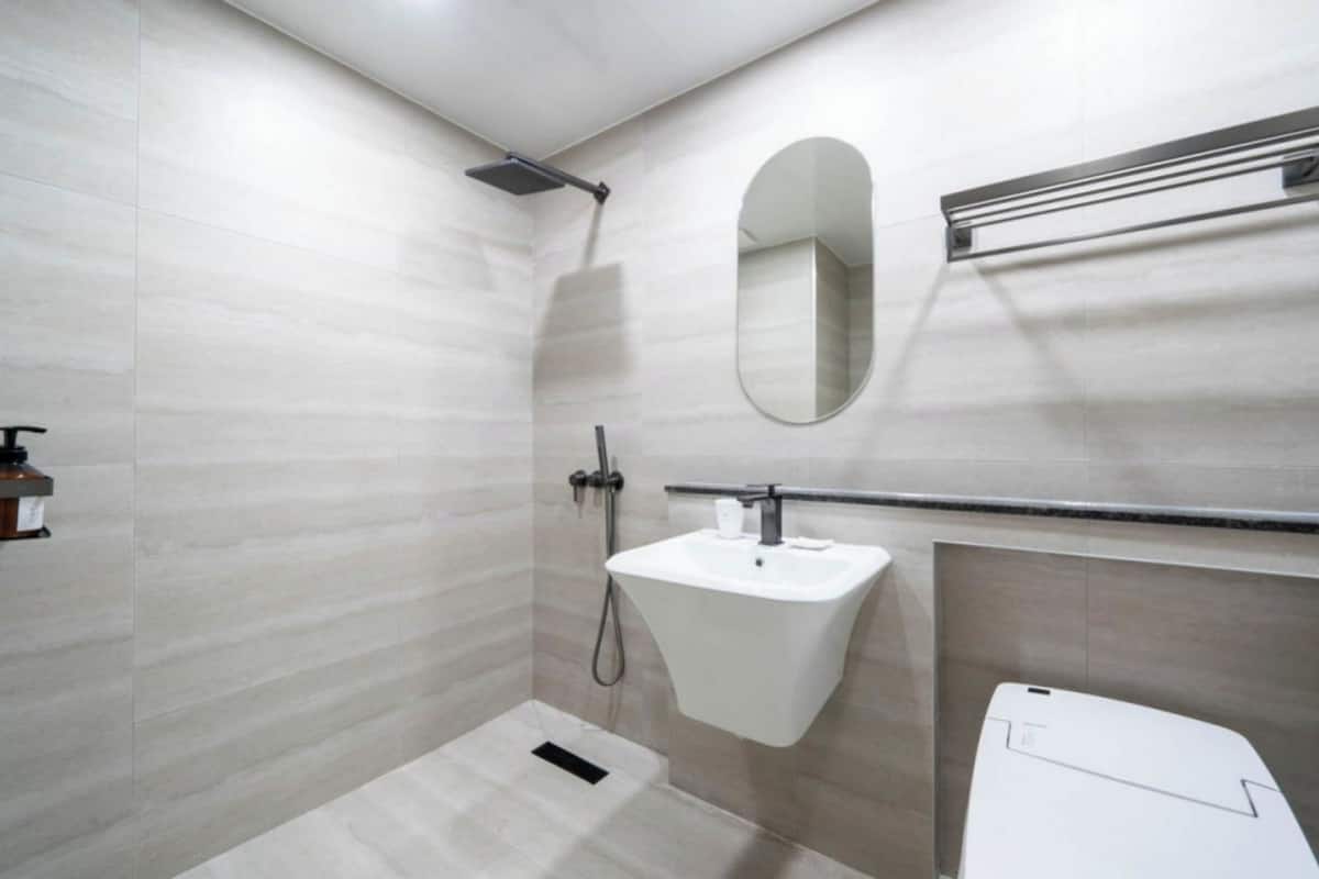 A bathroom with a shower, a sink, a mirror, and a toilet.