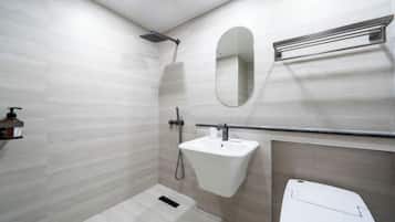 Un baño con ducha, lavamanos, espejo y retrete.