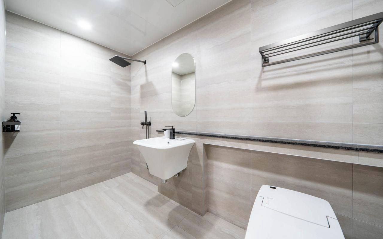 A modern bathroom with a white sink, a mirror, and a shower.