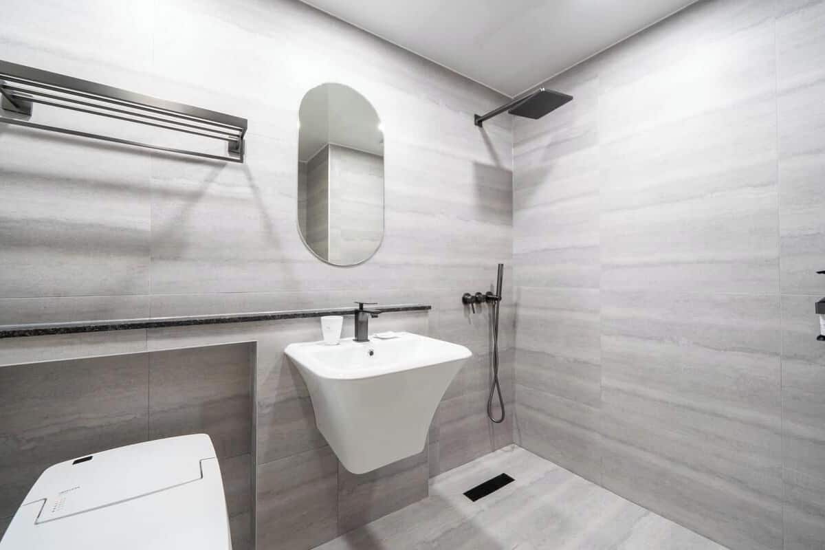 A modern bathroom with a white sink, a mirror, a towel rack, and a shower.