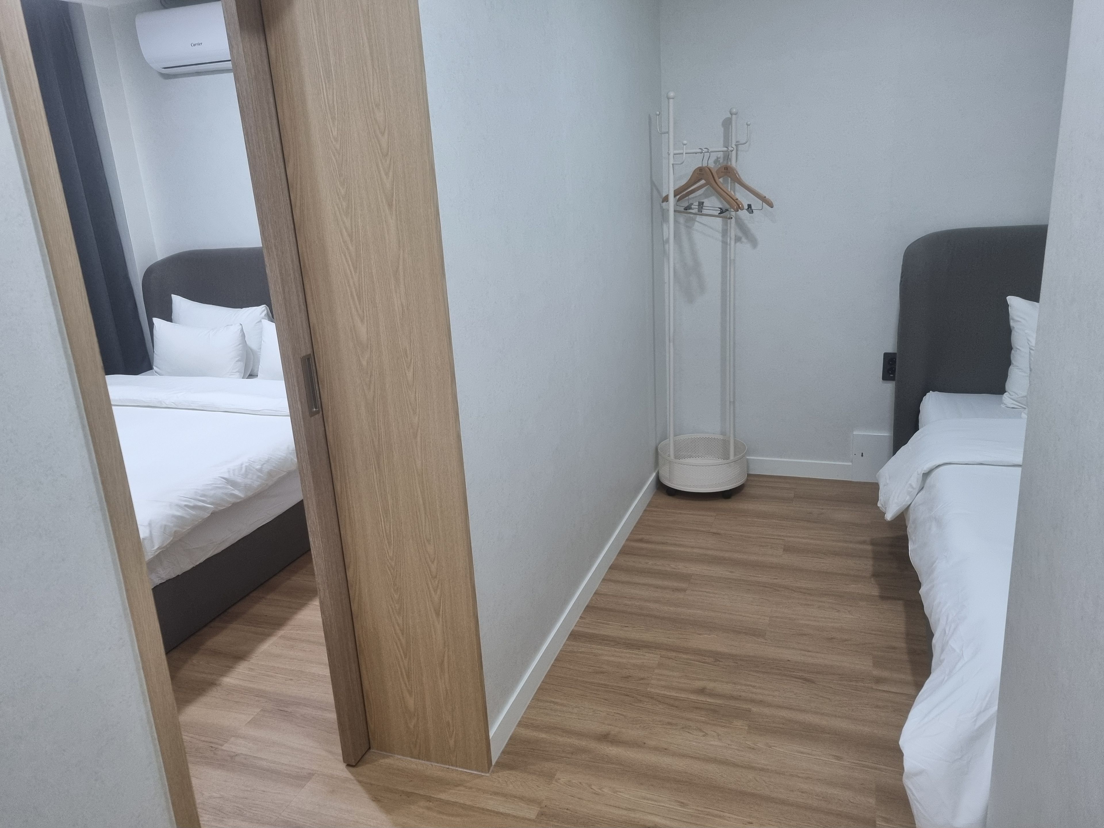 A hotel room with a bed, a wardrobe, a floor lamp, and a coat rack.