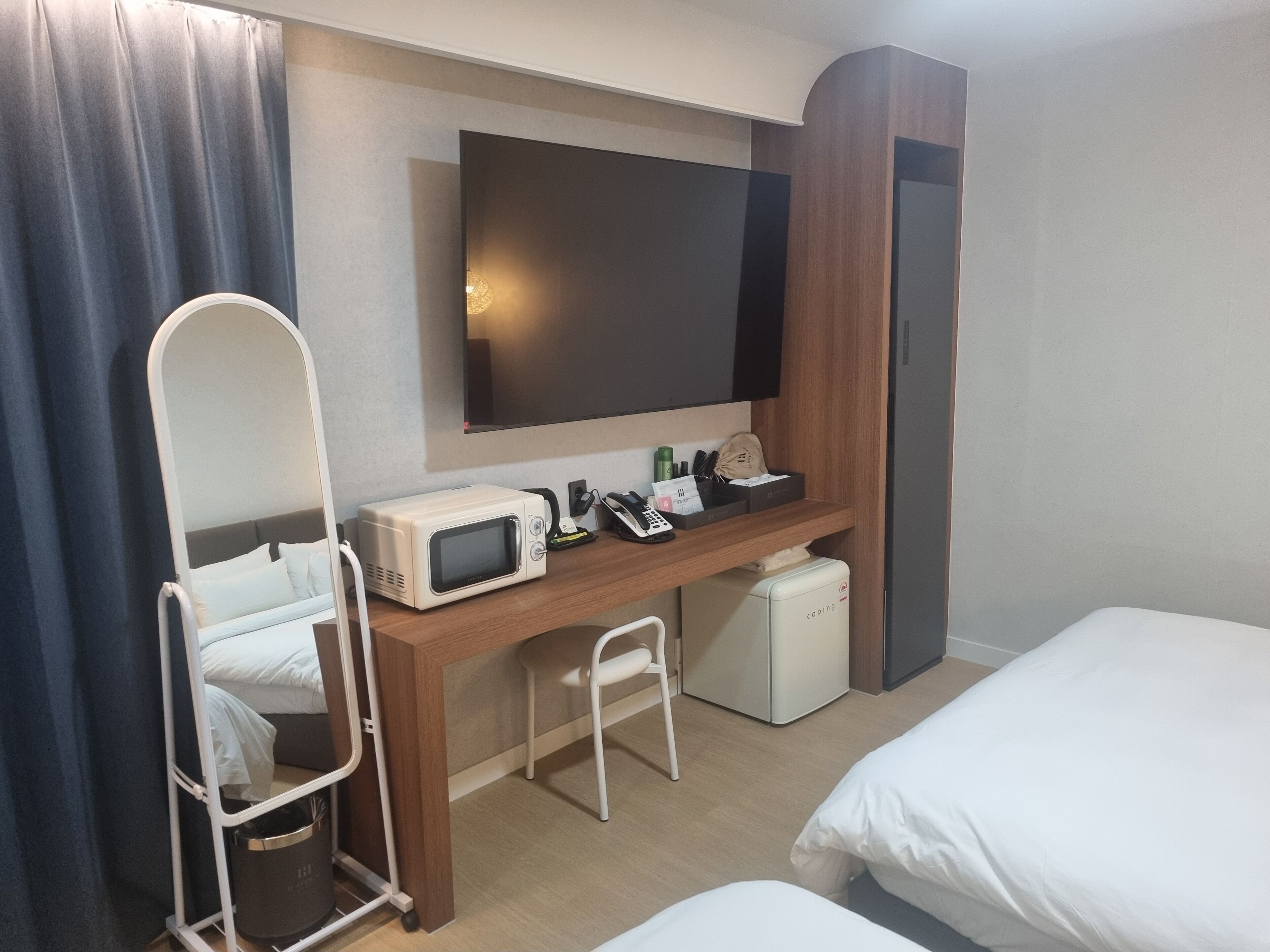 A hotel room with a bed, a desk with a microwave, a small fridge, a TV, and a chair.