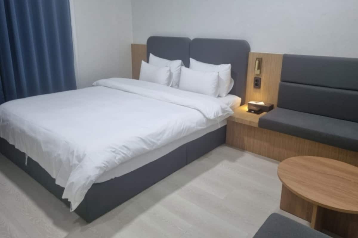 A modern hotel room with a bed, bedside table, and a small round table.