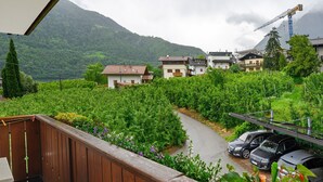 A balcony with a view of a vineyard, a road, and houses in the background. - Residence Sonngart Apartment A5 with View of Etschtal, Shared Pool, Hot Tub & Wi-Fi (Algund)