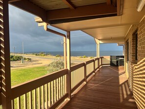A wooden deck with a view of the ocean and a paved road.