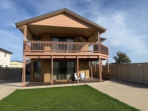 A two-story building with a balcony, a covered patio, and a fenced backyard. - B & B on Yorkes- 2 storey holiday home. Free Wifi, off peak special available (Edithburgh)