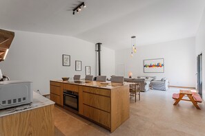 Une cuisine moderne avec des meubles en bois, un four encastré et un coin repas comprenant une table et des chaises.