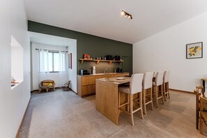 A modern kitchen with wooden cabinets, a dining area with a wooden table and chairs, and a view of the adjacent living space.