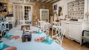 A dining area with a stone wall, white furniture, and a white cabinet with dishes. - Bed and Breakfast 'Chambre Bohème' with Private Terrace, Wi-Fi and Air Conditioning (Ryes)