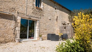 A stone building with a gravel driveway, a sliding glass door, and a wooden fence. - Bed and Breakfast 'Chambre Bohème' with Private Terrace, Wi-Fi and Air Conditioning (Ryes)
