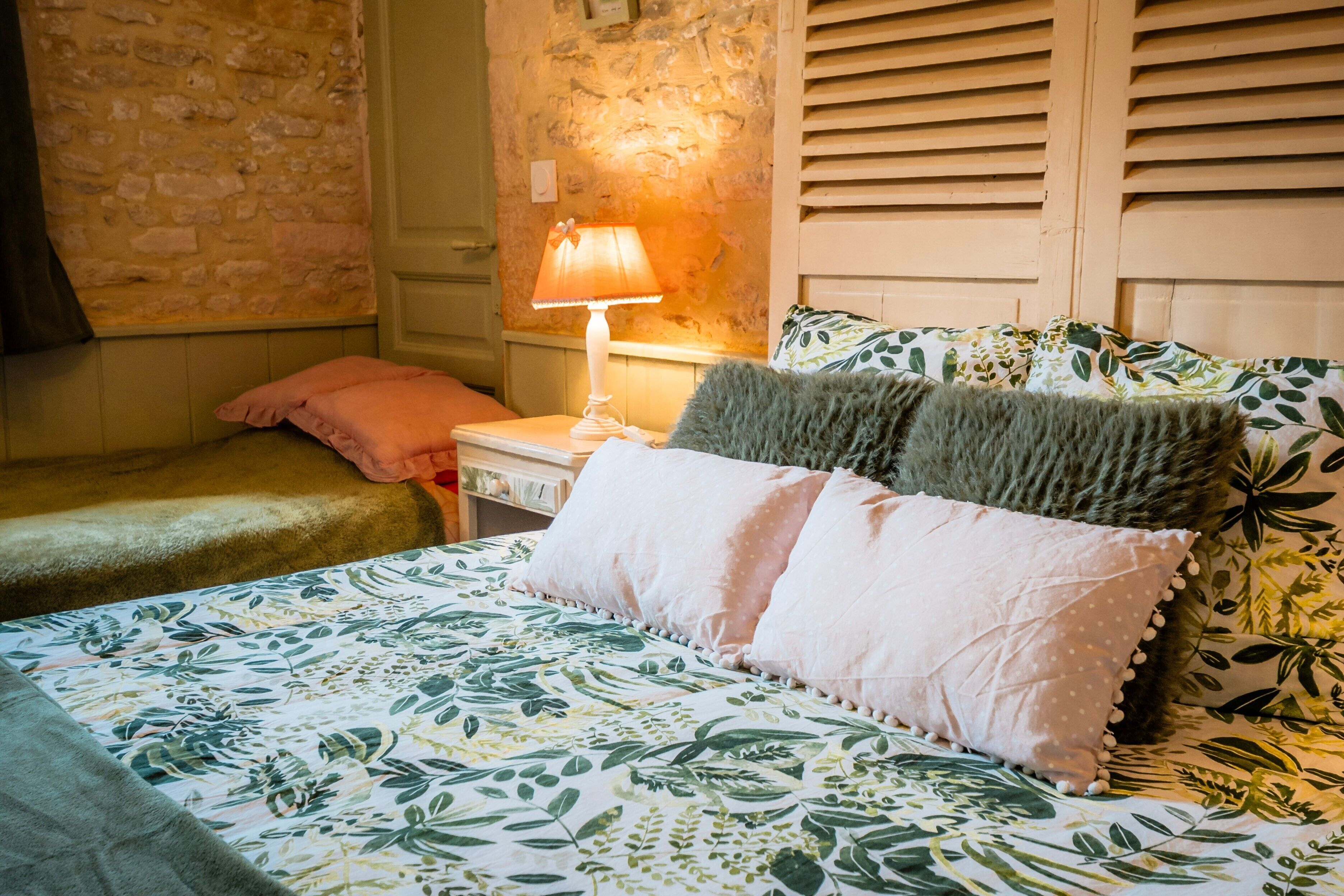A bed with floral bedding, a lamp, and a pillow.