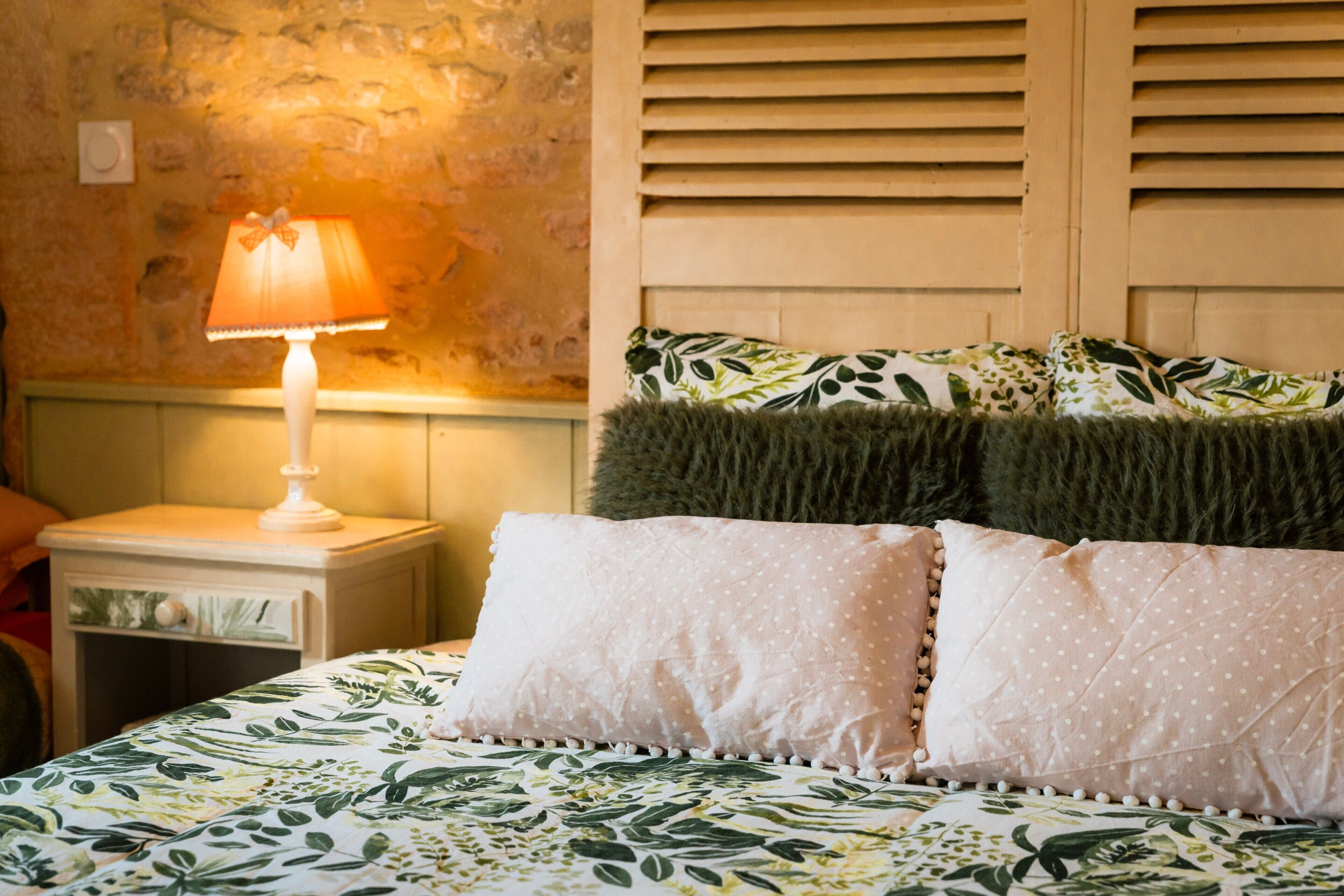 A bed with a floral bedspread, a lamp, and a nightstand with a drawer.