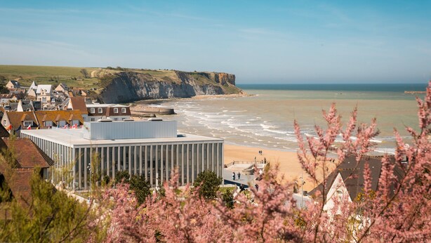 A coastal town with buildings, a beach, and cliffs.