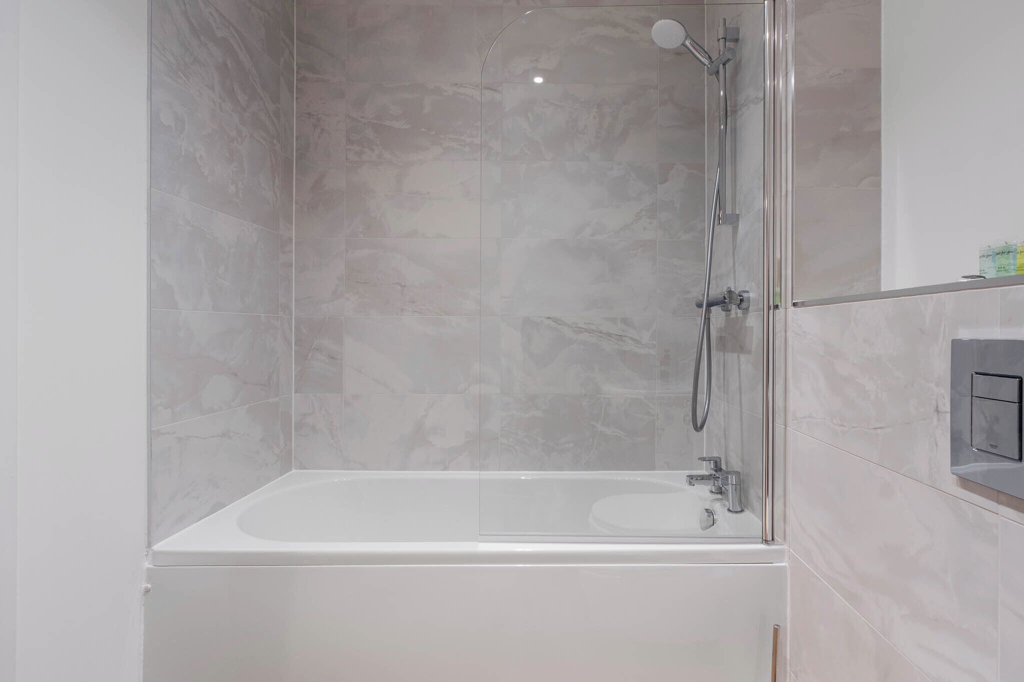 A modern bathroom with a glass-enclosed shower, a standalone bathtub, and a wall-mounted toilet.