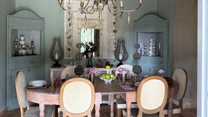 A dining room with a chandelier, wooden chairs, a table set with plates and flowers, and a stone ceiling. - Villa Rossi Danielli (Lazio)