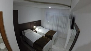 A hotel room with two beds, a nightstand, a mirror, and a window with curtains.
